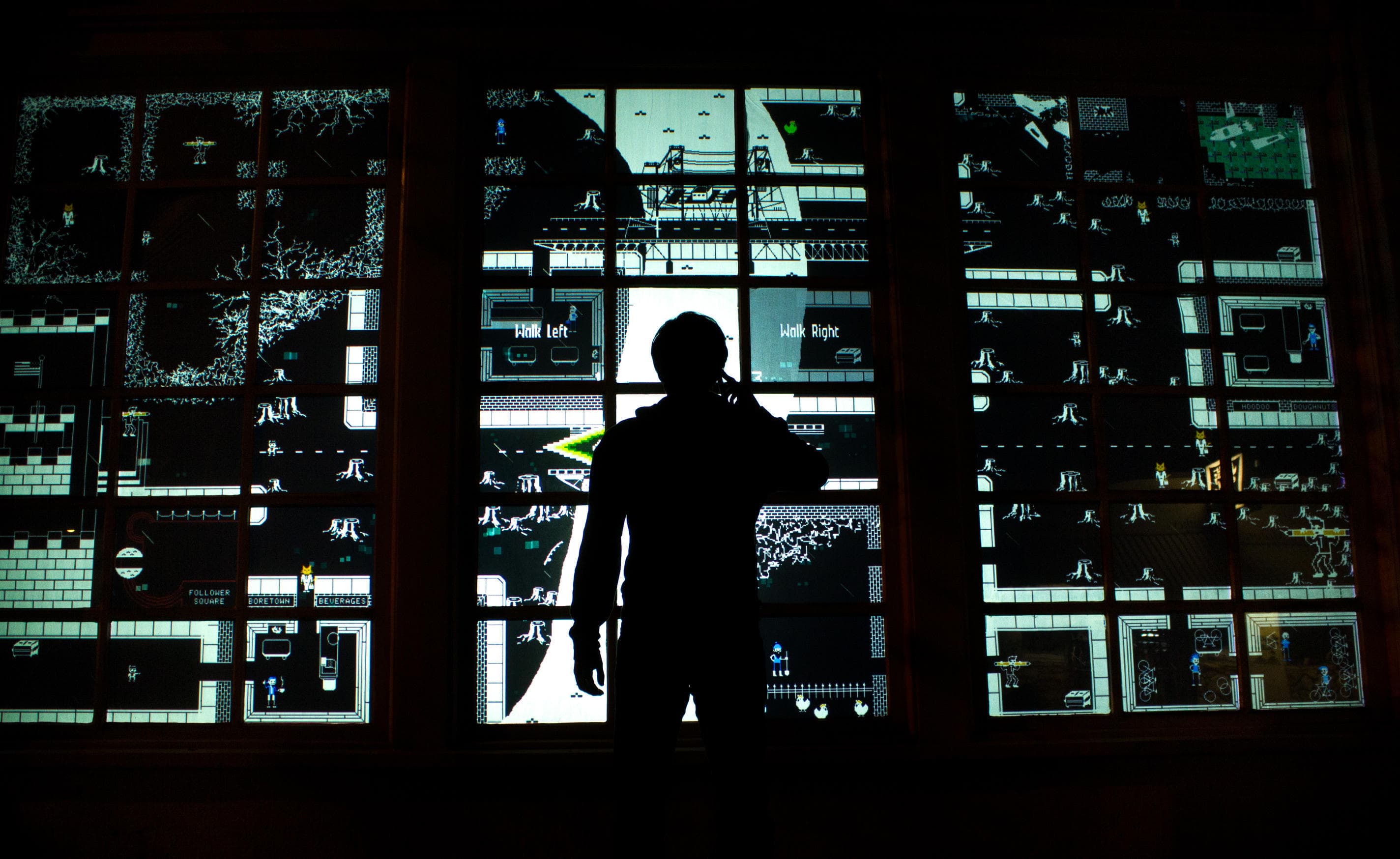 Person in silhouette standing in front of storefront windows displaying an isometric RPG based on Portland, OR culture.